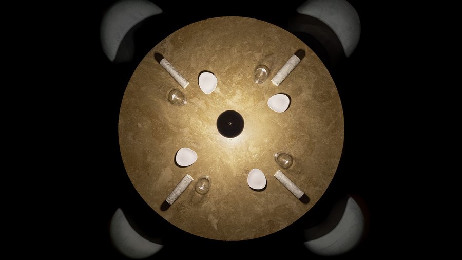 Un disco dorato su fondo nero, con piccoli elementi bianchi e di vetro disposti a raggiera