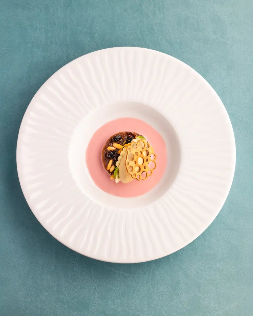 Un dessert su piatto rosa con una cupola di cialda dorata