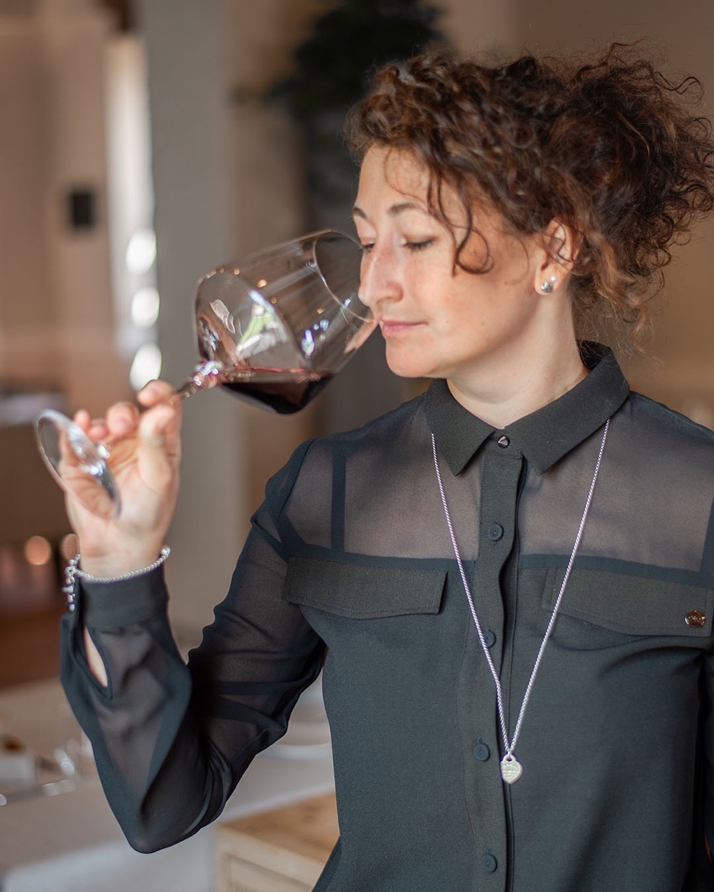 La sommelier Michela Bigio annusa un calice di vino rosso nella sala del ristorante