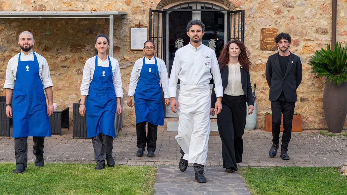 La squadra di sala e cucina de La Sosta del Cavaliere davanti alla facciata in pietra