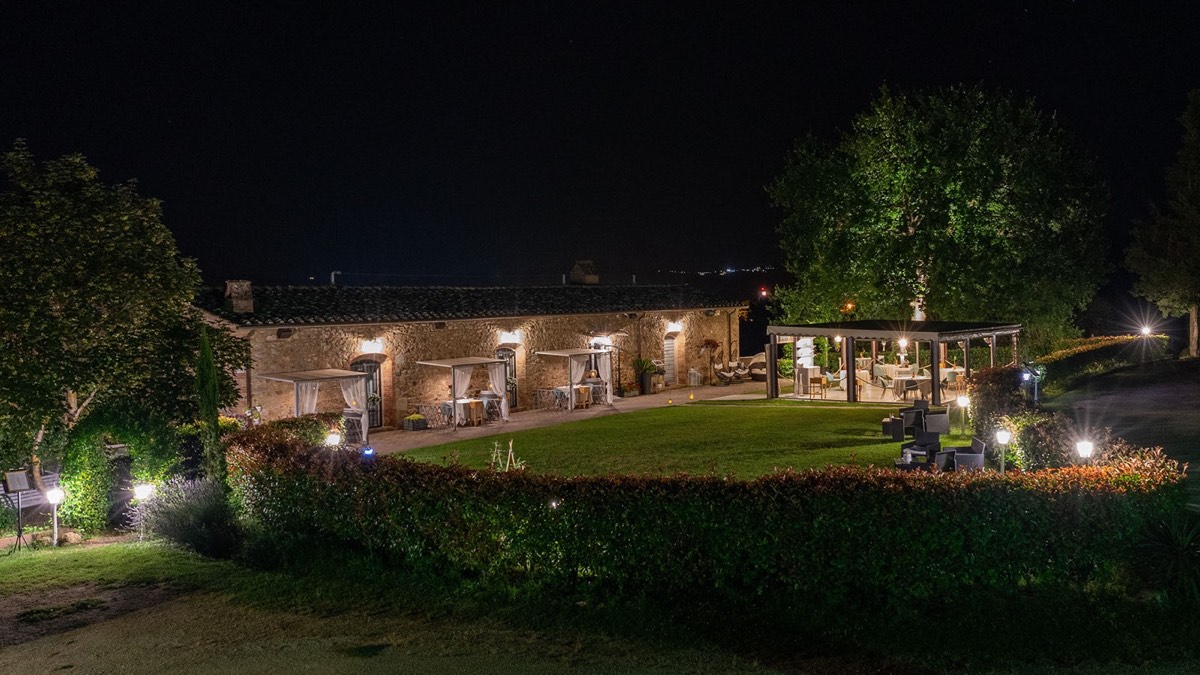 Il vecchio fienile in pietra di Torri all’ora blu, con il prato e la veranda illuminata